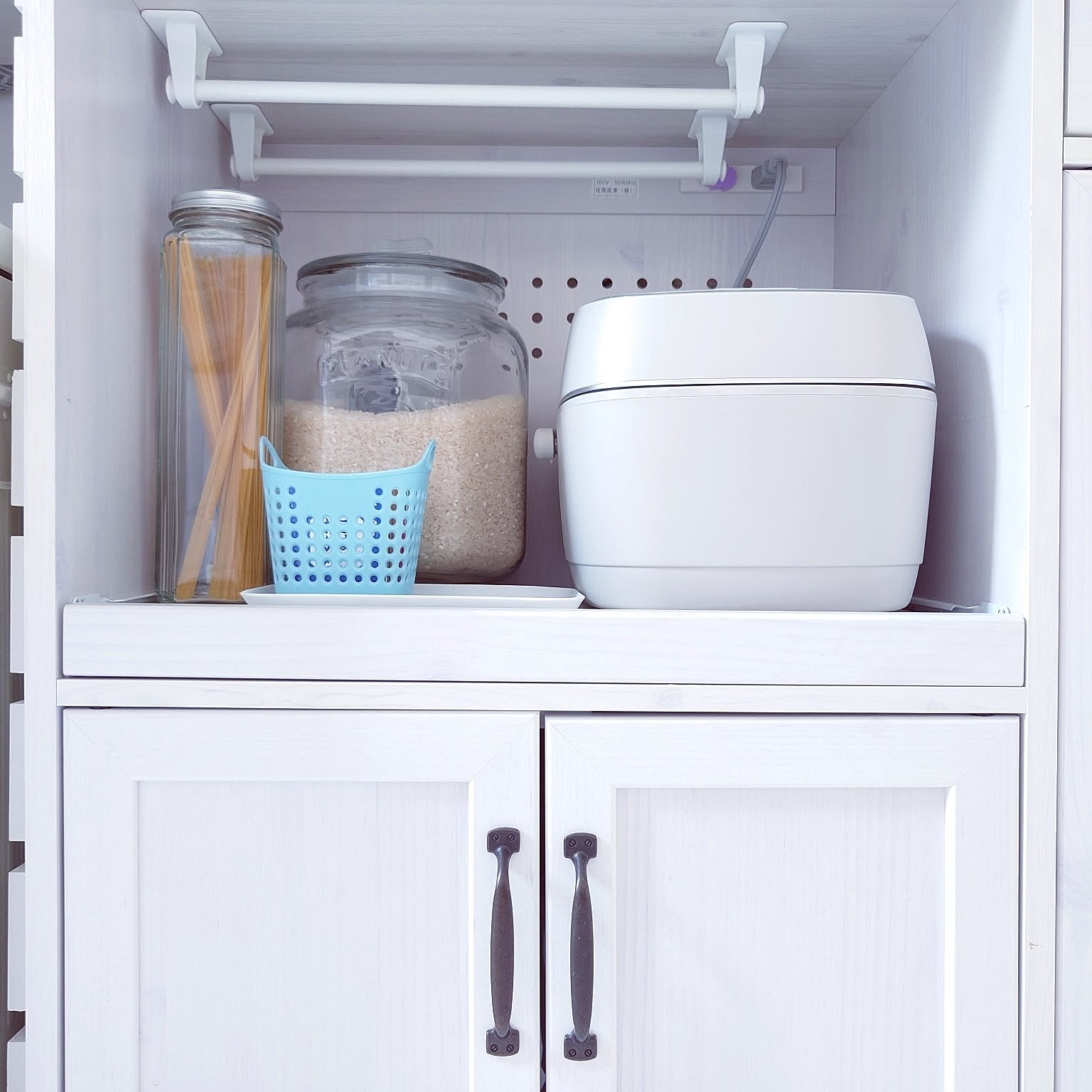 A greige 5.5-cup Zojirushi rice cooker fitted neatly into a kitchen storage zone.