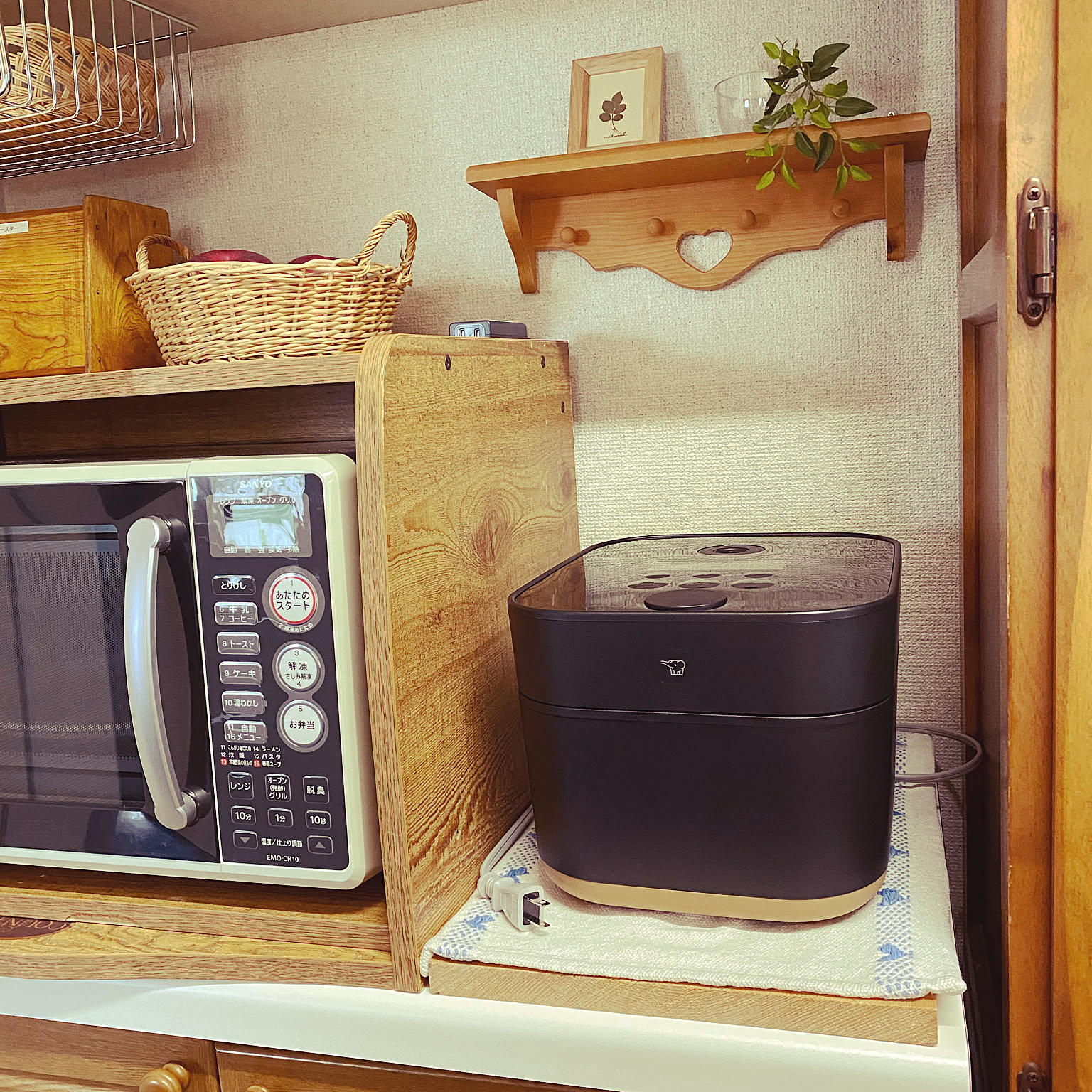 A black Zojirushi STAN. rice cooker shown close-up beside a retro microwave.