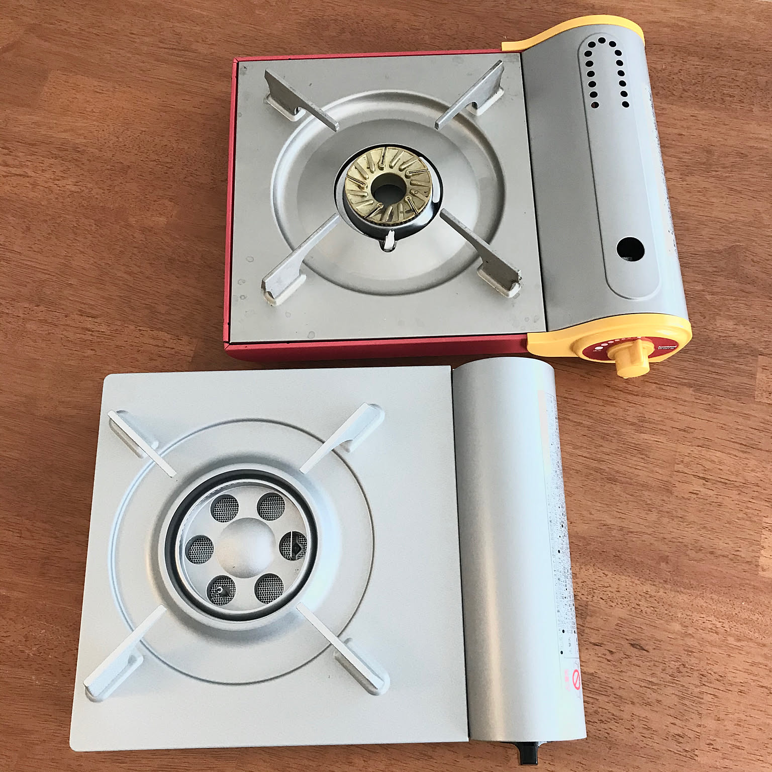 An Iwatani Eco Premium cassette stove shown clearly on a wood table beside another compact stove.