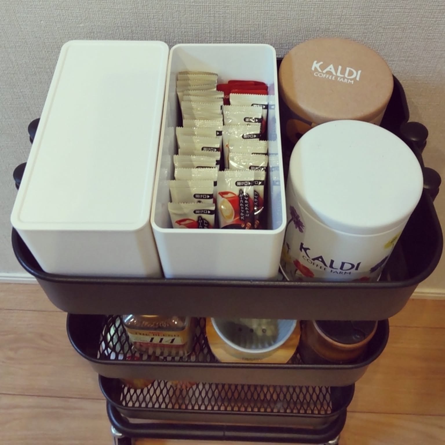 Coffee filters, packets, canisters, and a tower case arranged on a rolling cart.