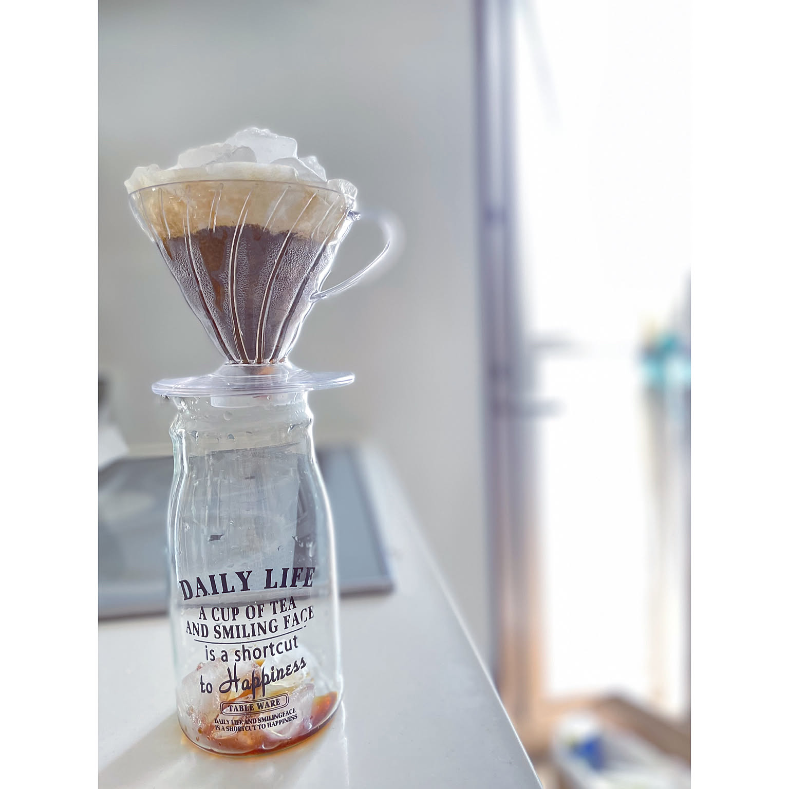A clear HARIO V60 plastic dripper brewing coffee on a small glass server.