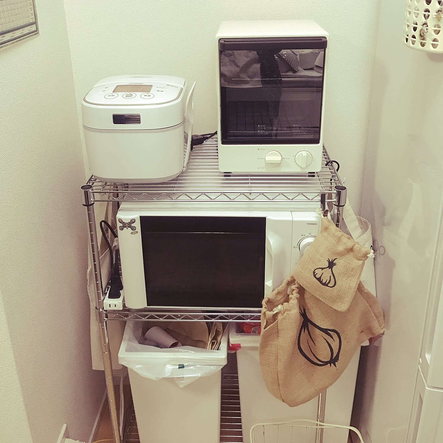 A white Tiger tacook rice cooker placed on a compact appliance rack.
