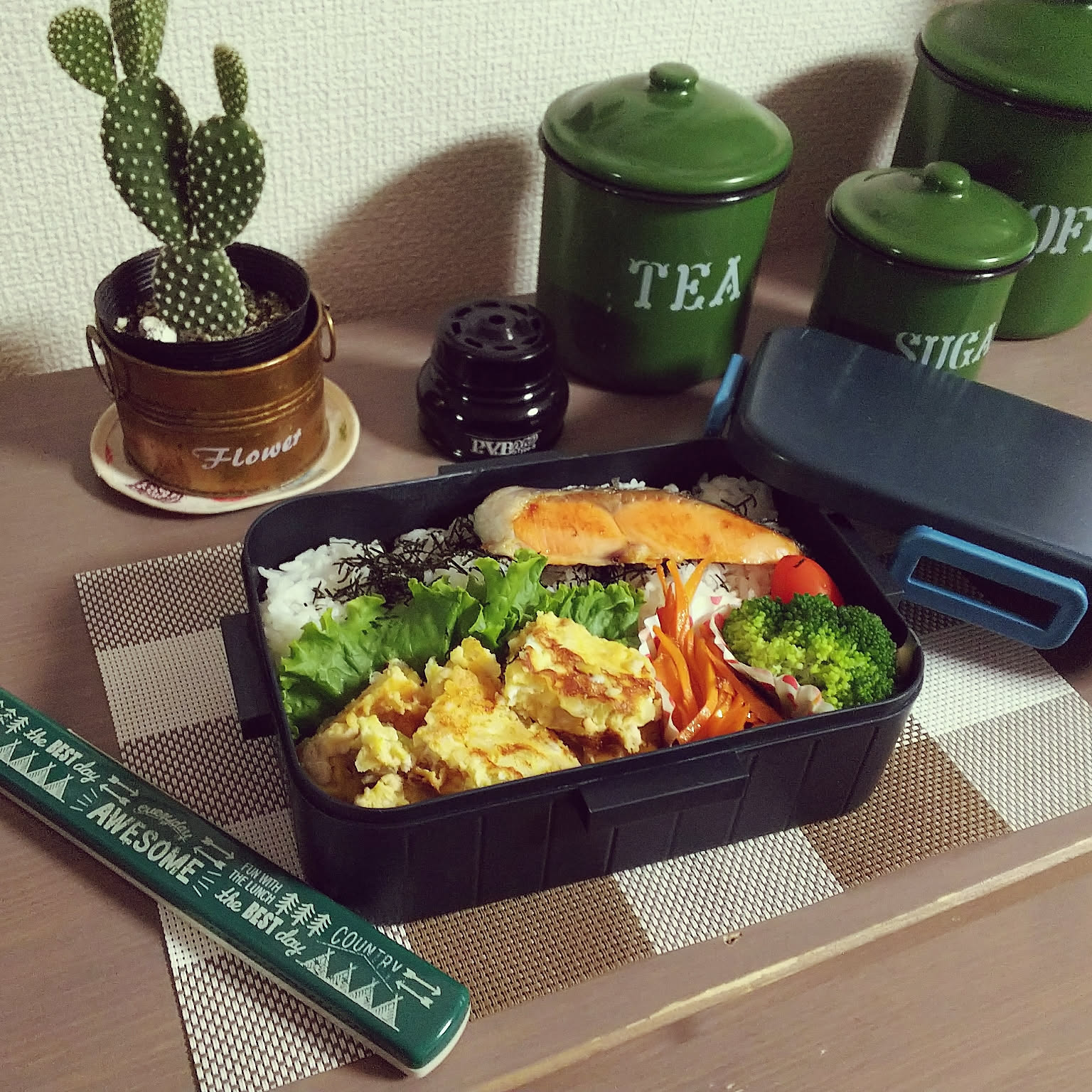 A deep black 650ml four-lock bento box packed with rice, salmon, eggs, vegetables, and chicken.