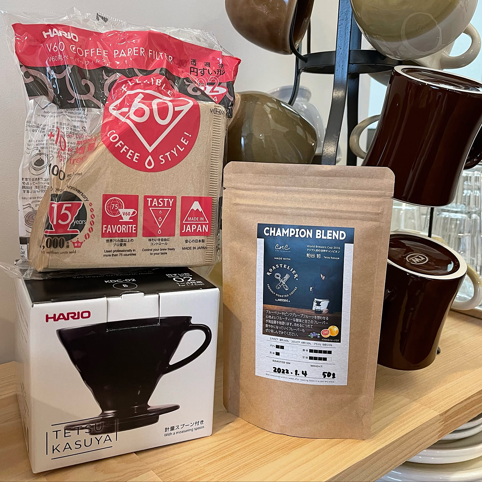 HARIO V60 02 paper filters and a black V60 02 dripper package displayed beside coffee beans.