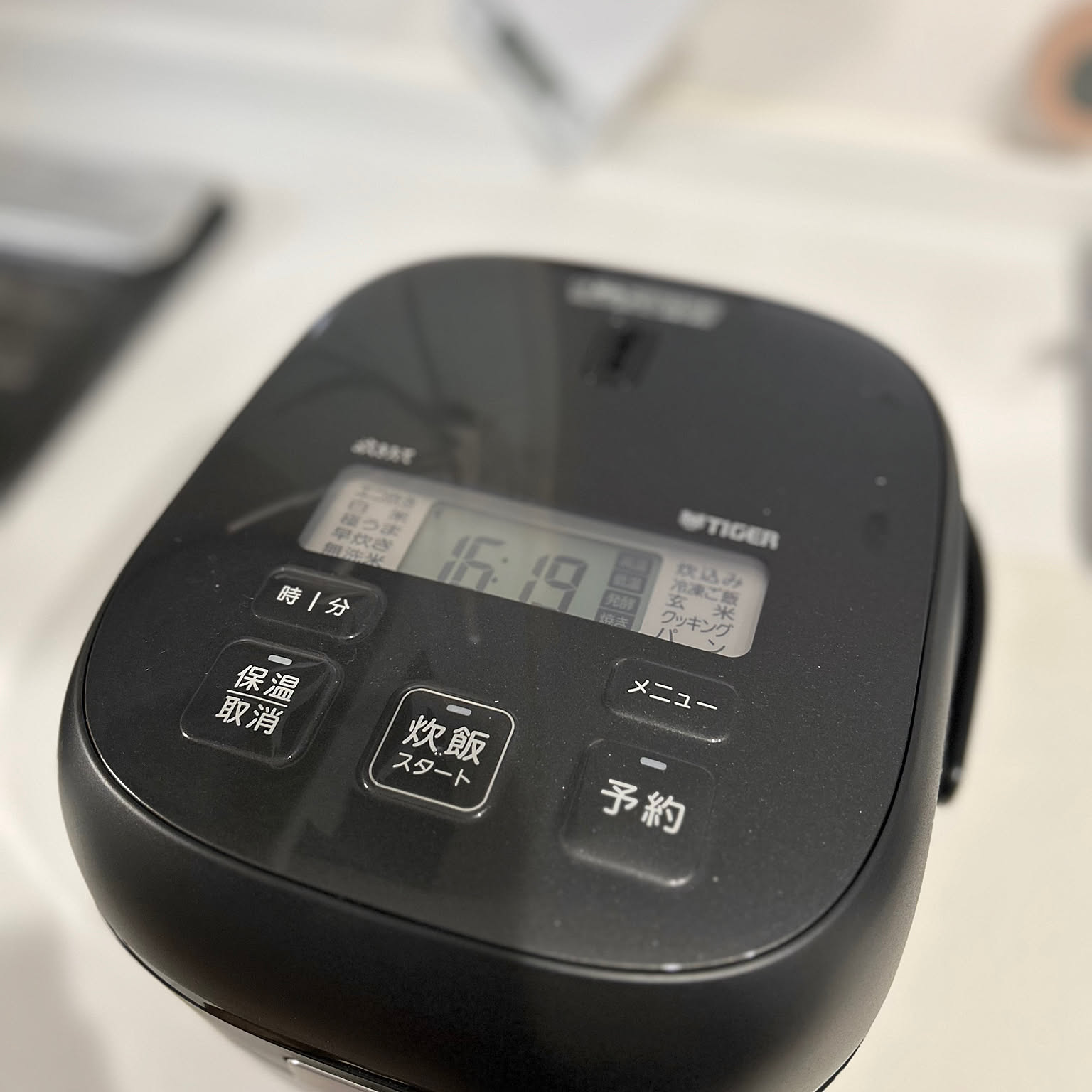 Close-up of a black Tiger rice cooker control panel showing cooking buttons and LCD display
