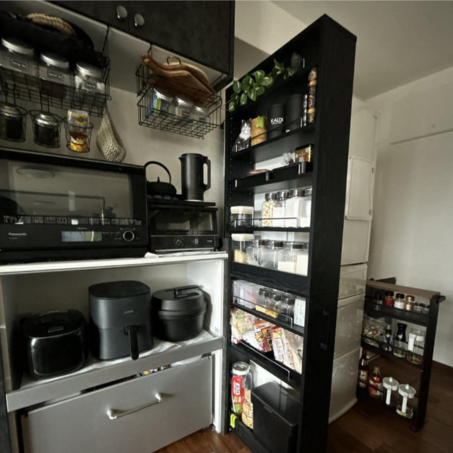 A Japanese kitchen with spices and dry goods organized on a slim rolling rack beside the refrigerator and countertop appliances.
