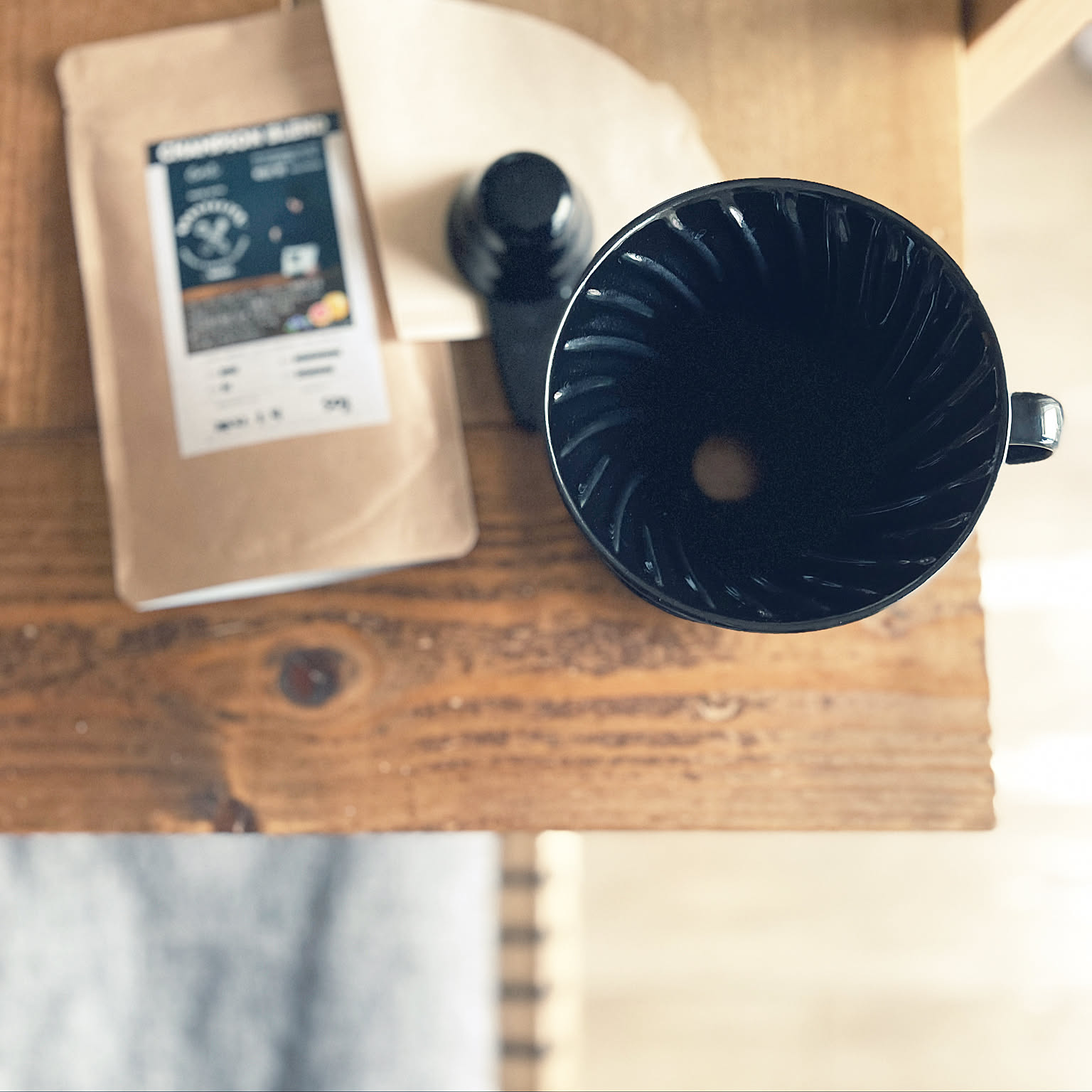 A black HARIO V60 02 dripper photographed from above with coffee beans and filters.
