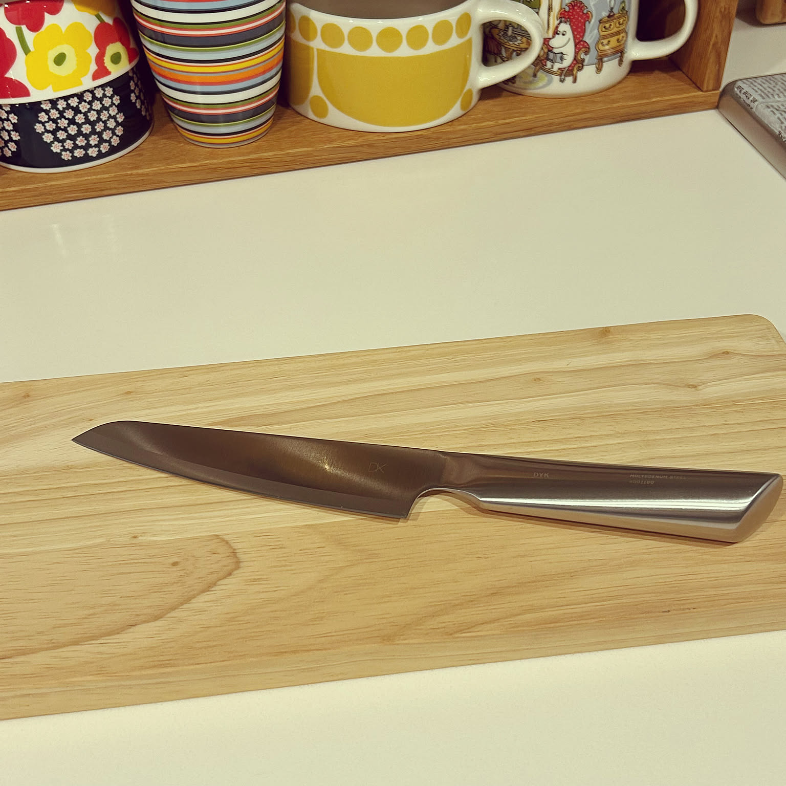 Small Japanese kitchen knife resting on a wooden cutting board.