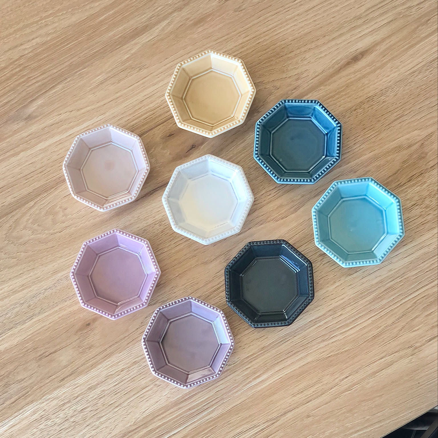 Colorful octagonal Japanese small plates arranged on a wooden table.