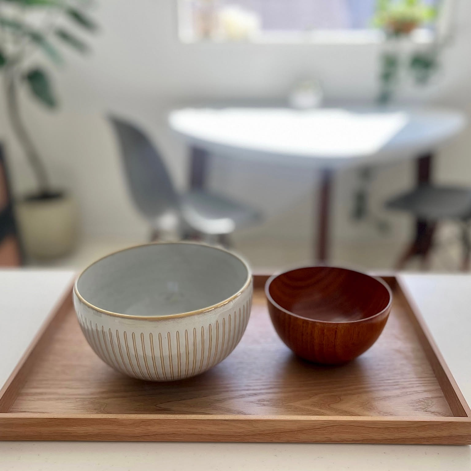 A Japanese donburi bowl and wooden soup bowl shown side by side on a tray.