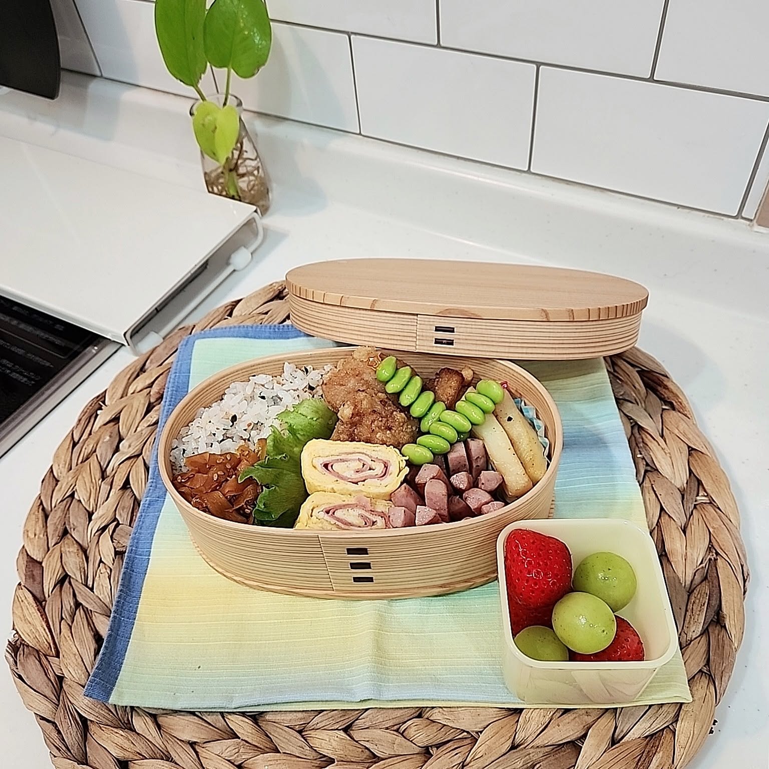 Open Odate Kogeisha oval magewappa bento packed with rice, meat, egg, vegetables, and fruit.