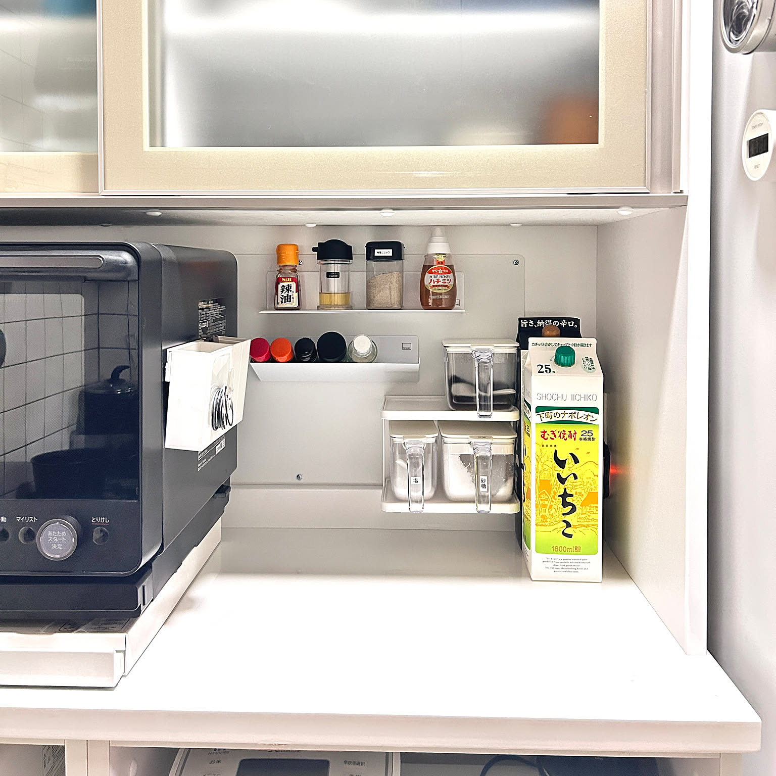 Yamazaki Tower magnetic shelves and containers creating a compact seasoning zone between a toaster oven and refrigerator.