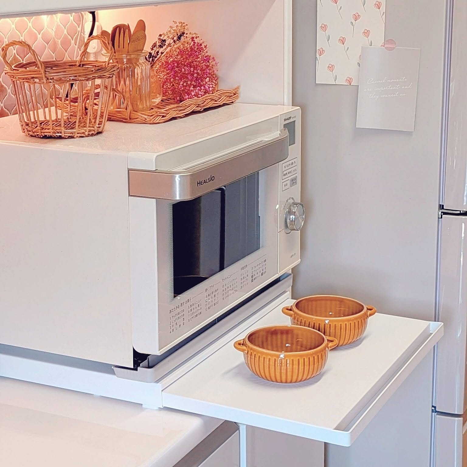 A white Yamazaki Tower pull-out shelf under a microwave creating temporary serving space on a compact kitchen counter.