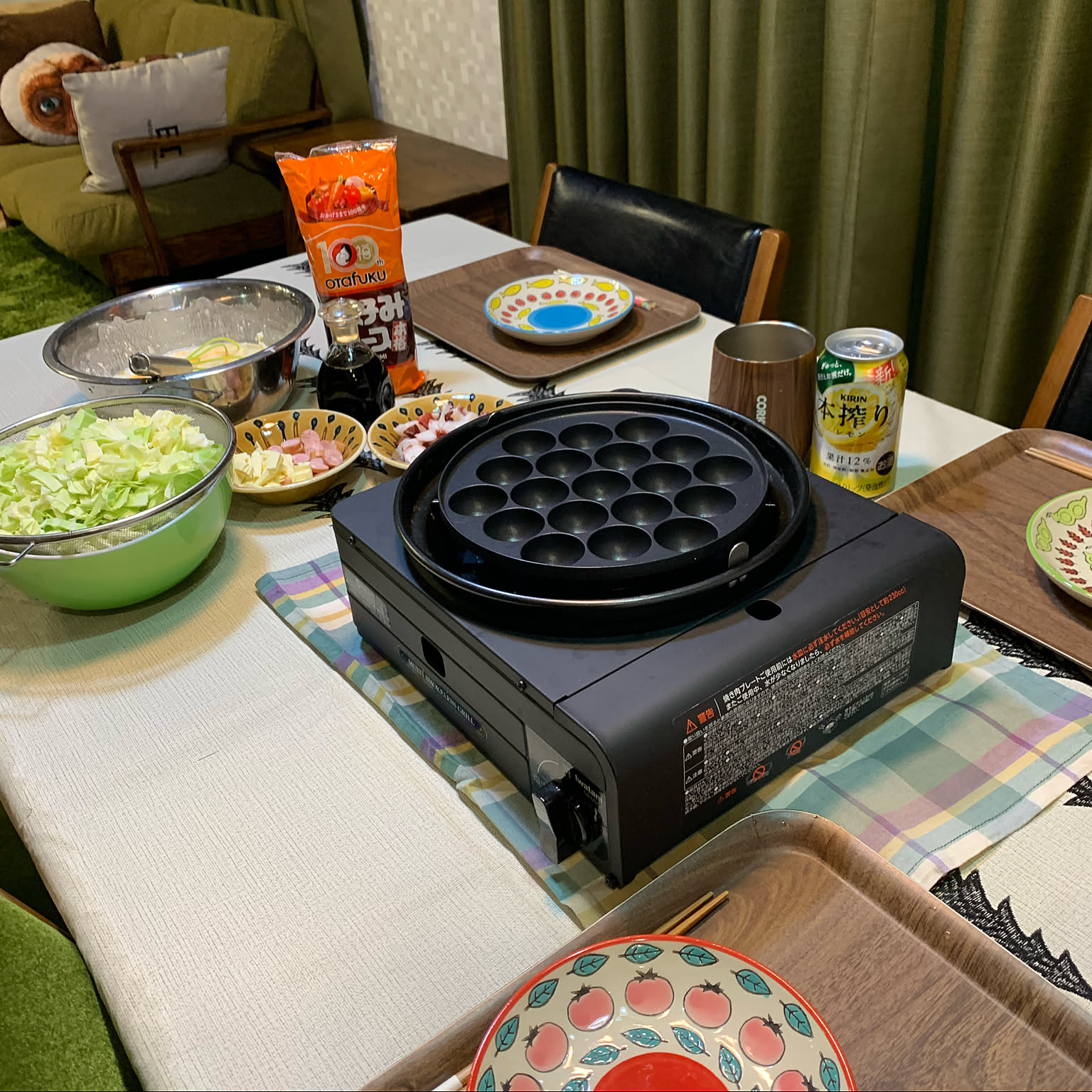 An Iwatani tabletop takoyaki grill set up with batter and toppings on a dining table.