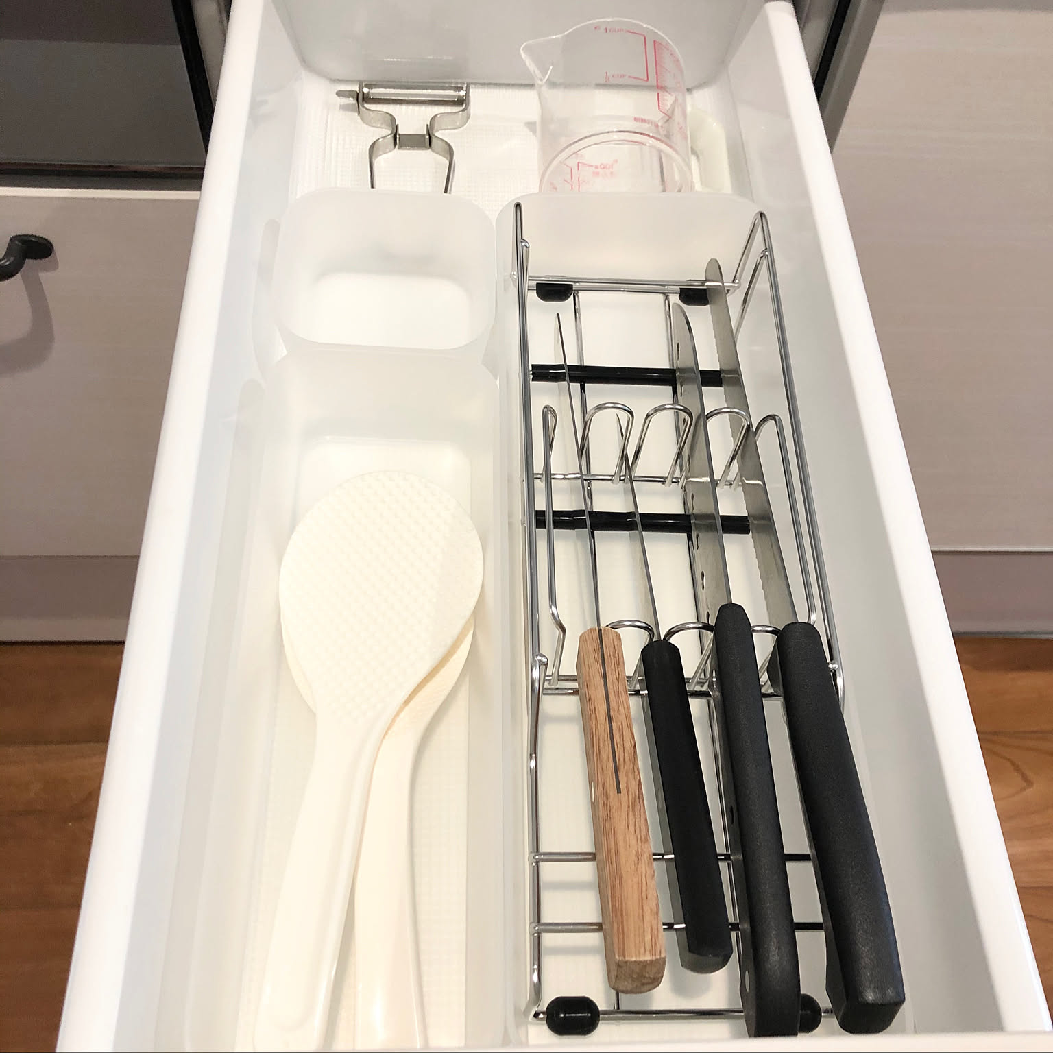 Kitchen drawer with knives stored in a slotted metal knife organizer.
