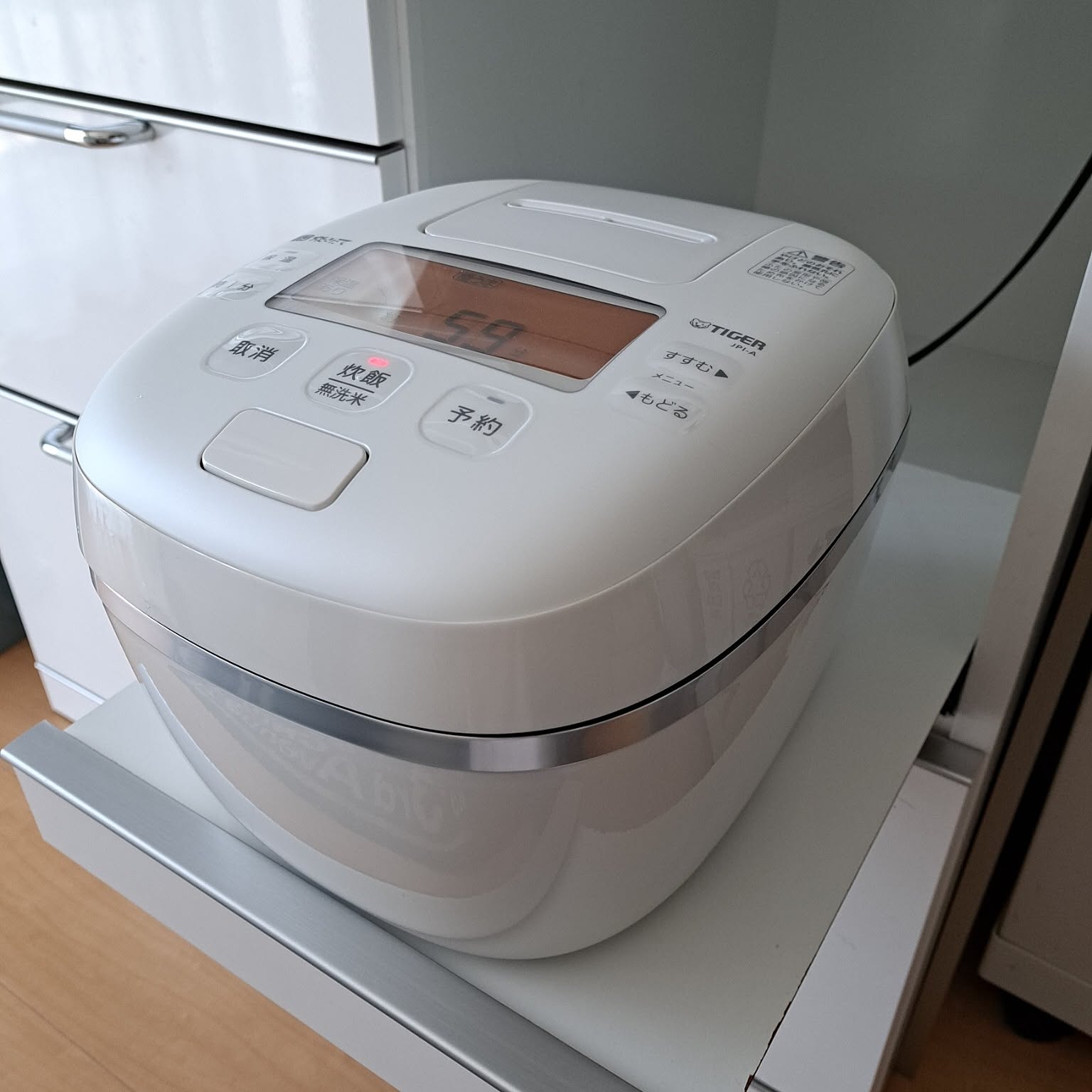 A white Tiger rice cooker placed on a slide-out appliance shelf.