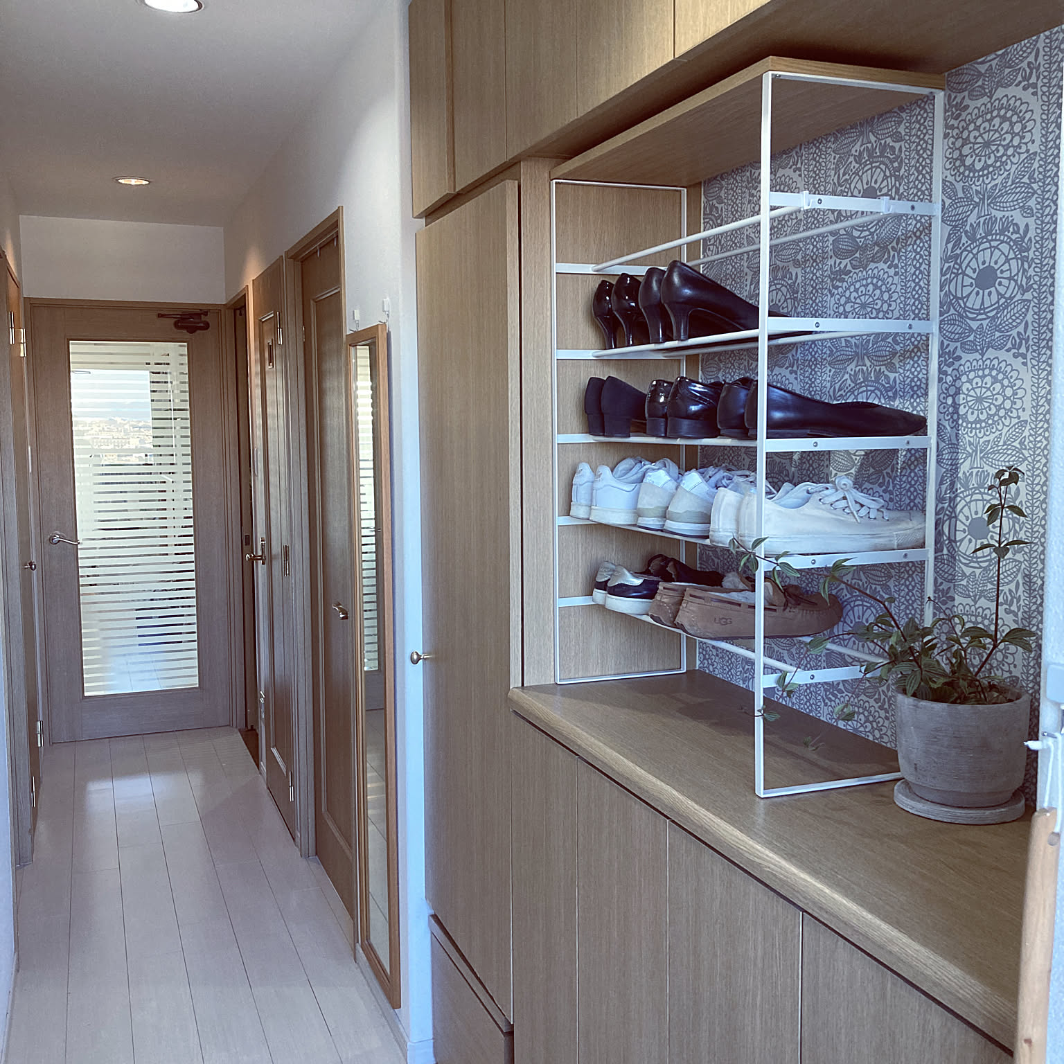 A white tower shoe rack keeping an apartment entryway tidy in a Japanese home.