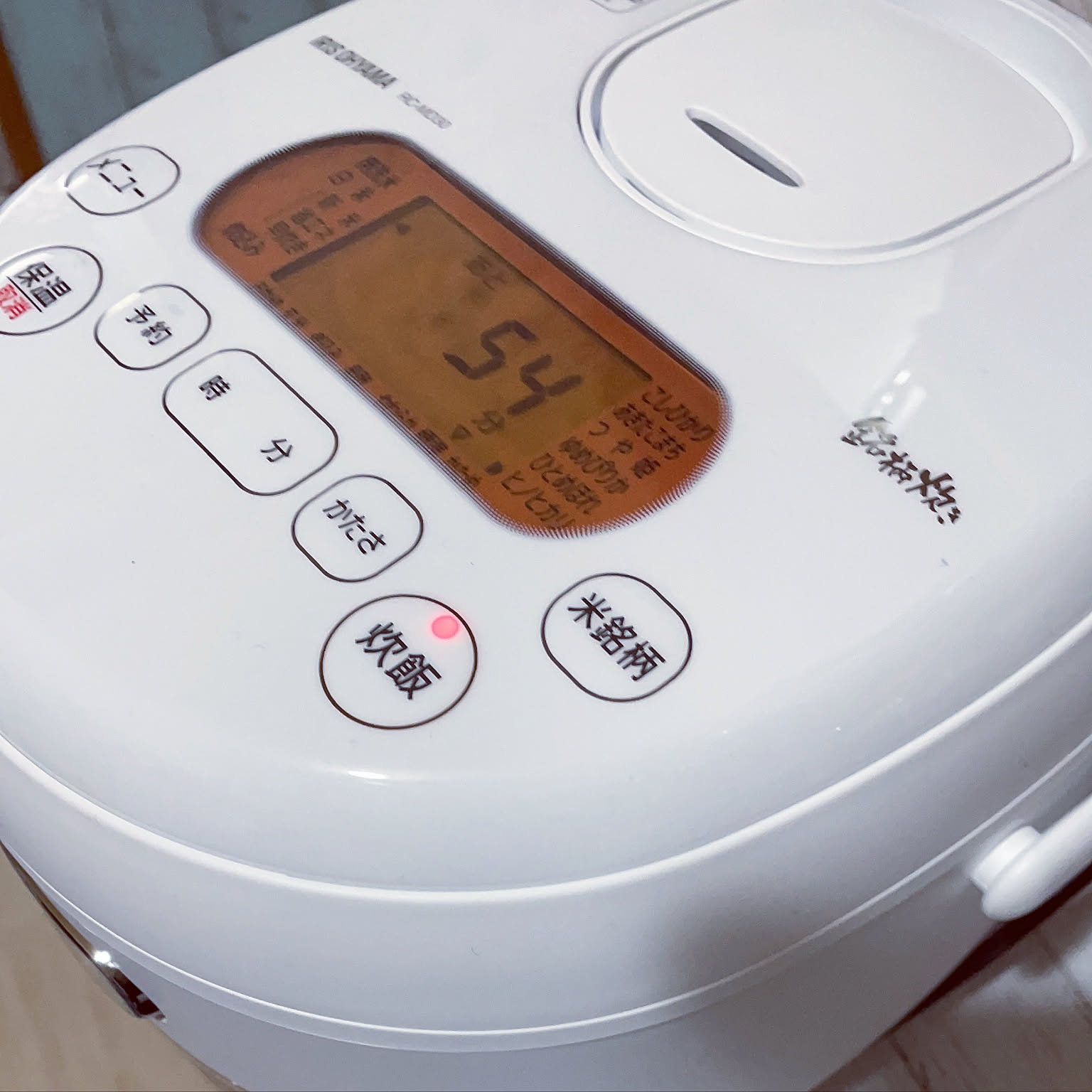 A close-up of a white 3-cup rice cooker control panel in use.