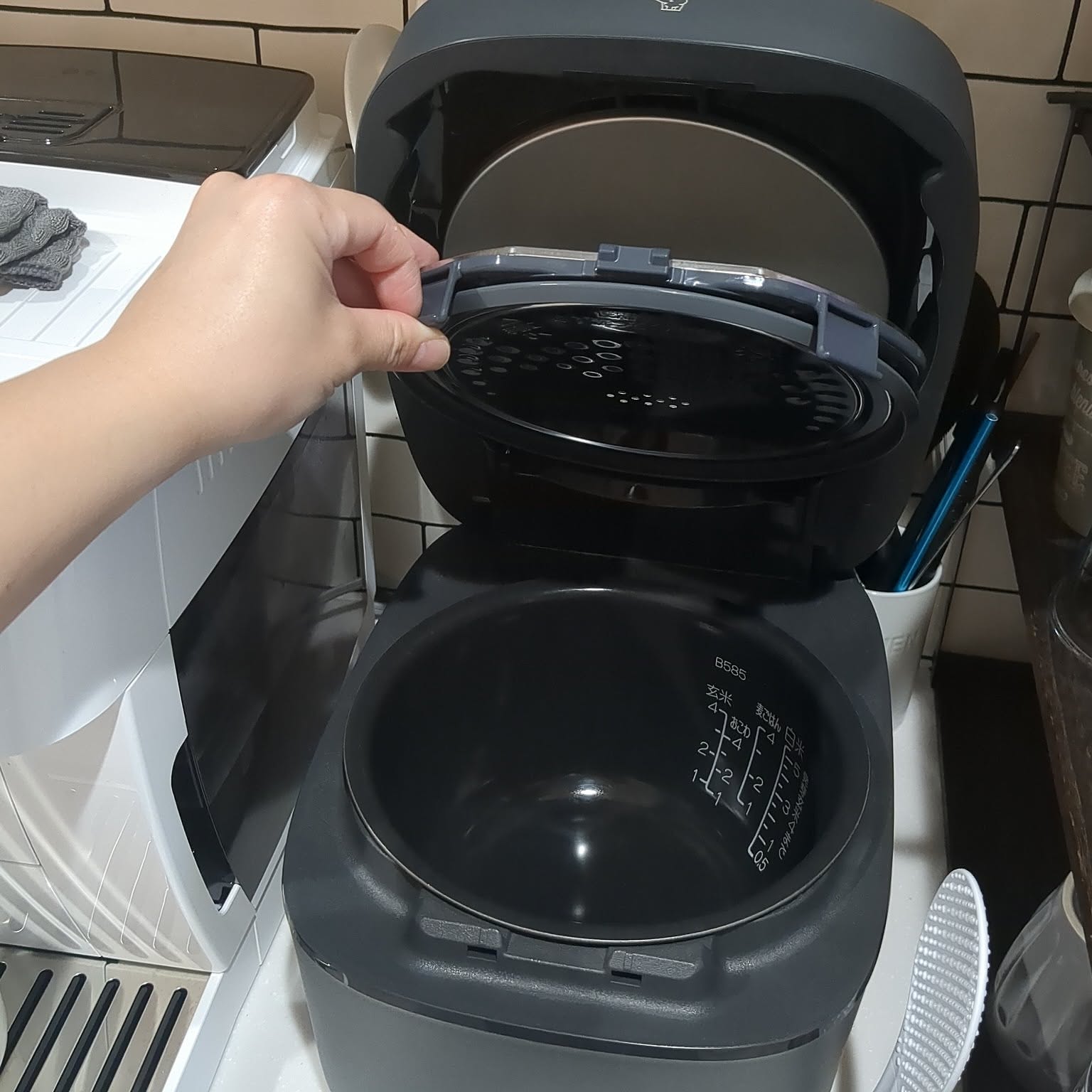 A black Zojirushi rice cooker shown open from above with the inner lid visible.