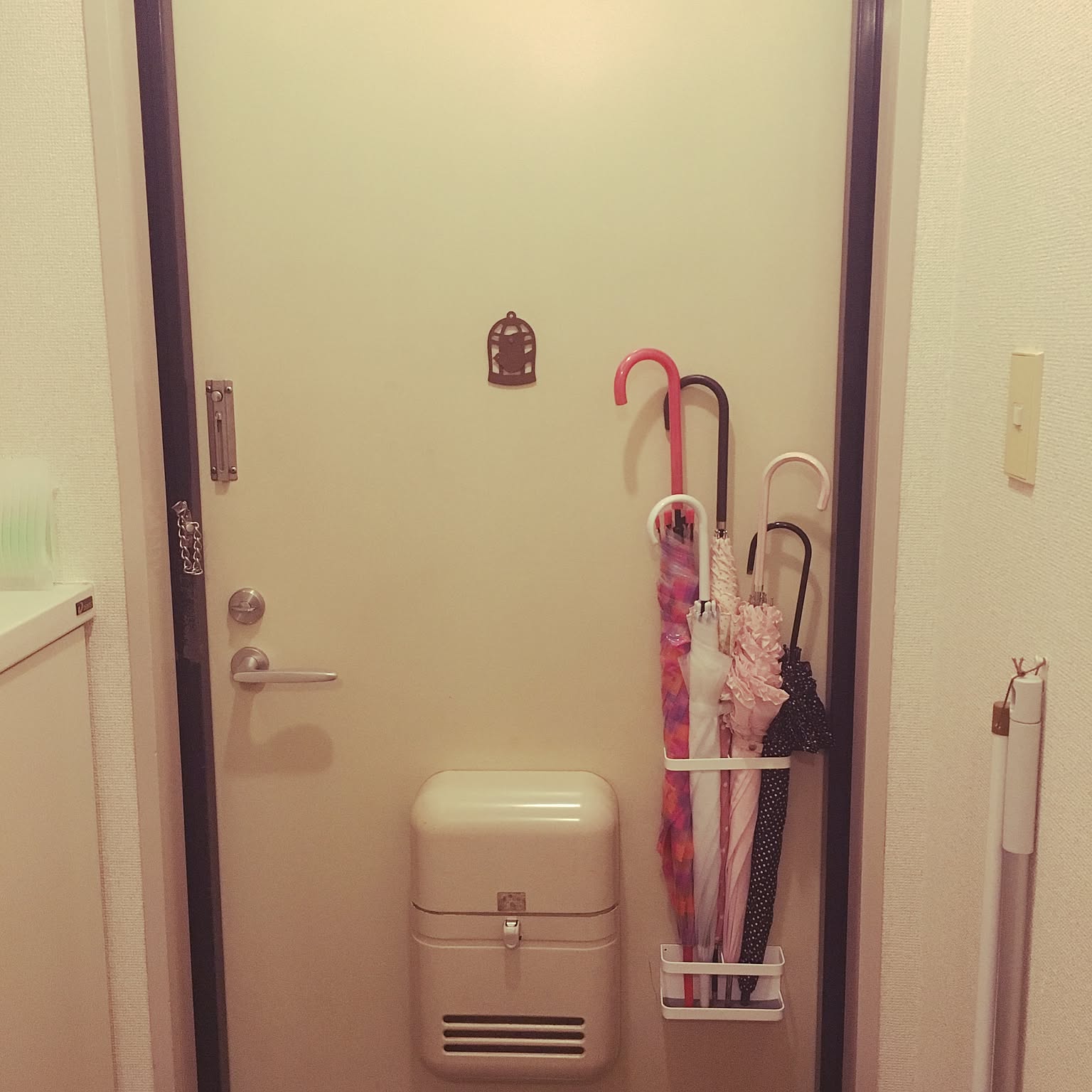 A magnetic umbrella stand mounted to an apartment entry door in a small Japanese home.
