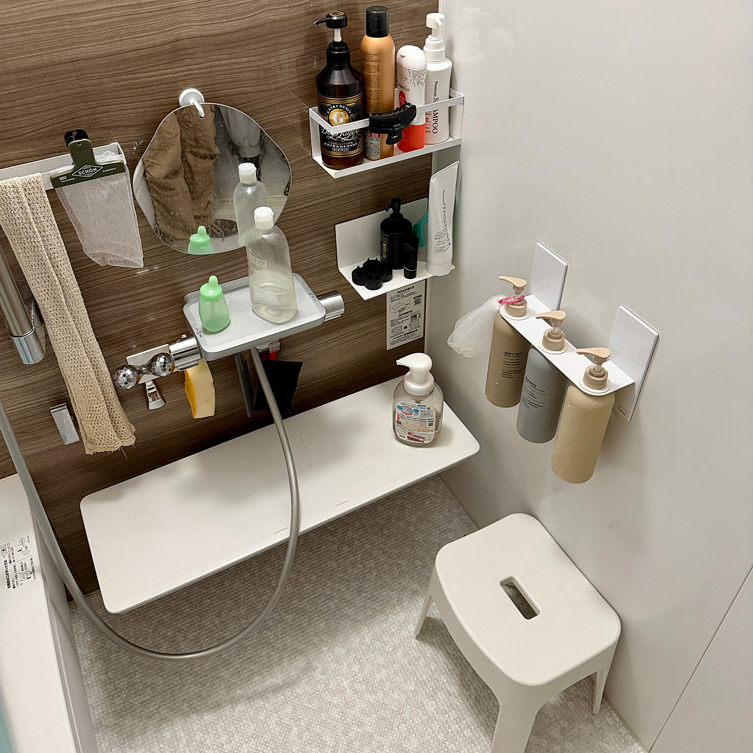 A Japanese unit bathroom with shampoo dispensers, trays, and hooks all mounted on magnets against the steel wall panels