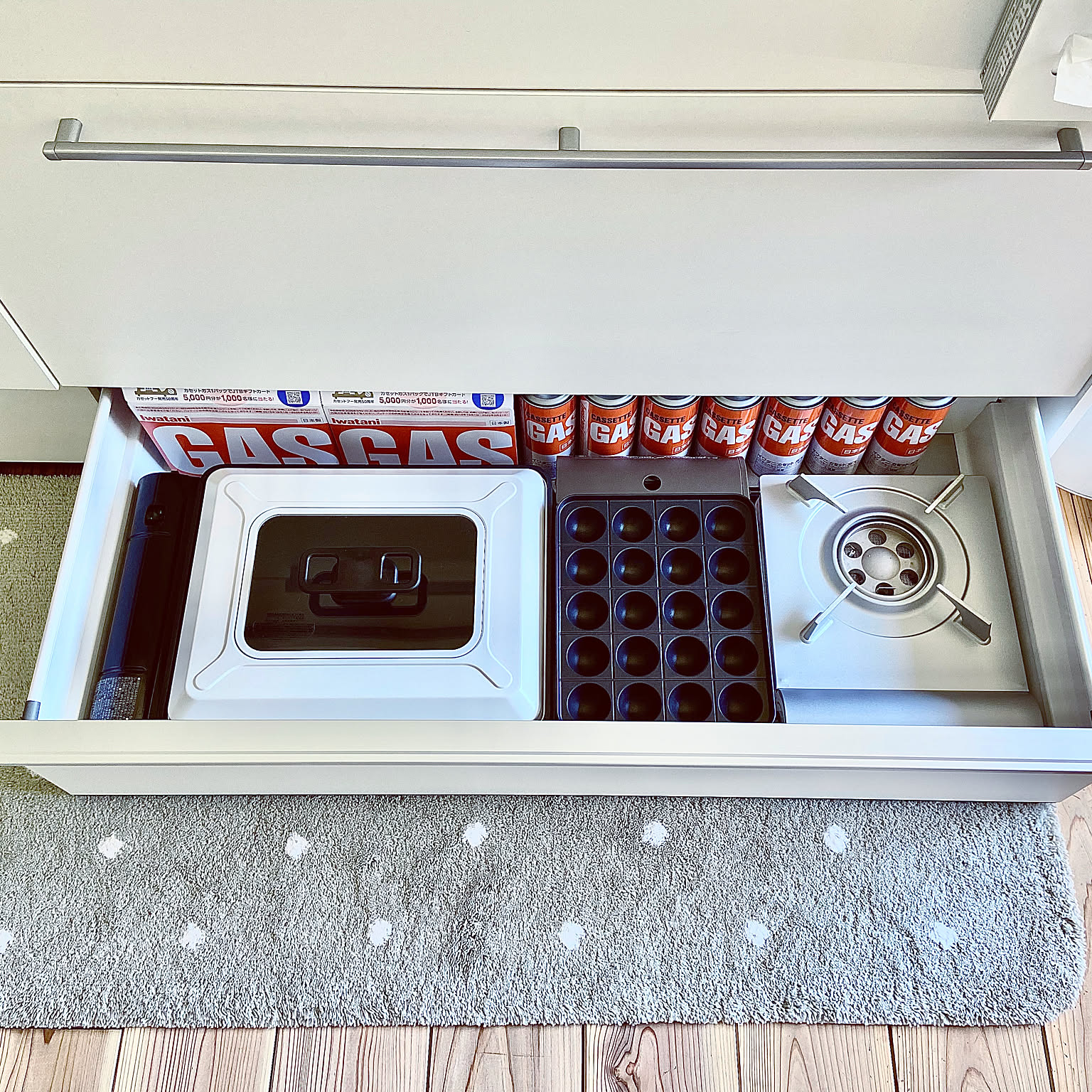 A kitchen drawer holding butane gas canisters and a cassette stove for emergency storage.
