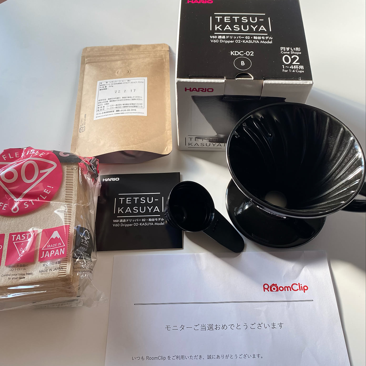 A HARIO V60 02 dripper package with paper filters, coffee beans, and a measuring spoon.