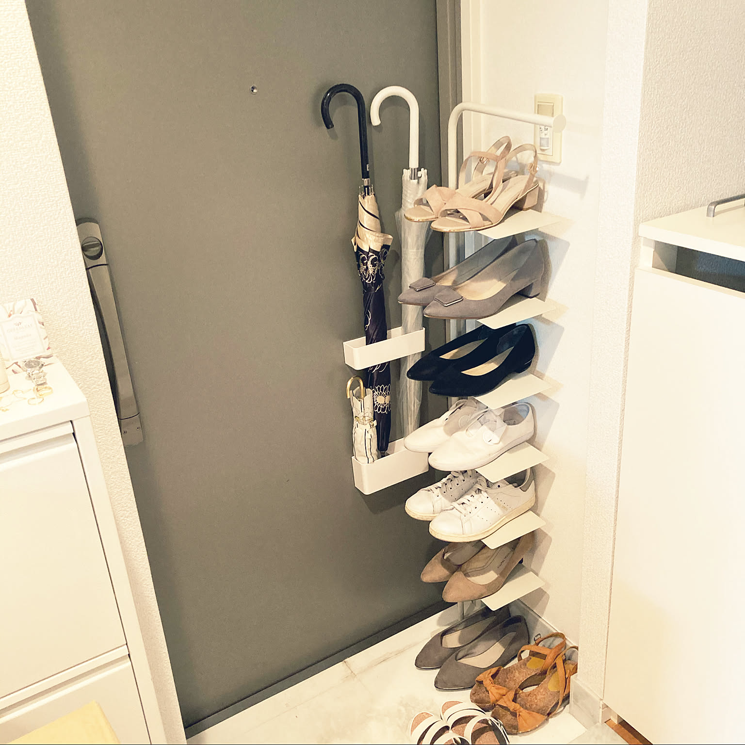 A compact entryway using a slim shoe rack and magnetic umbrella storage on the door.
