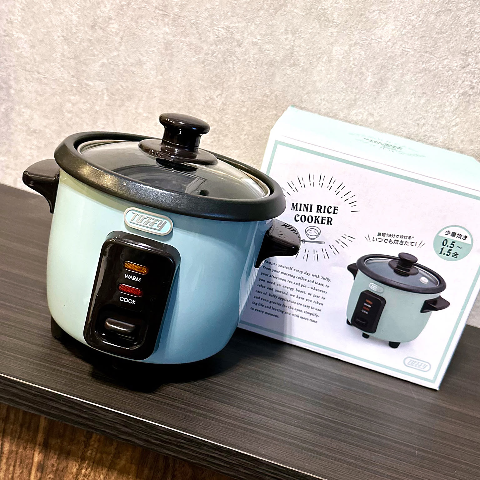 A blue Toffy mini rice cooker shown beside its box on a table.