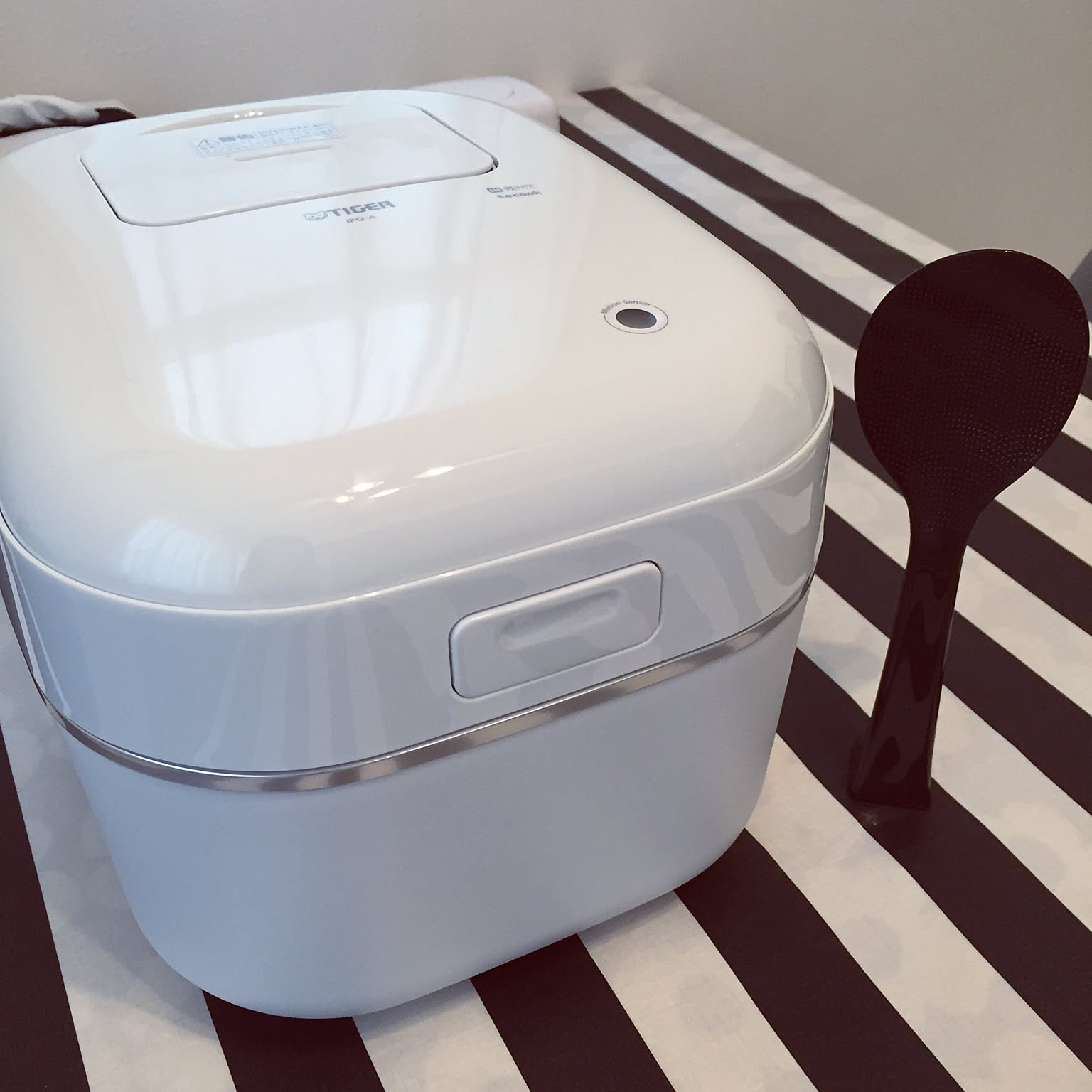 A white Tiger JPQ-A100-W 5.5-cup rice cooker shown clearly in close-up.