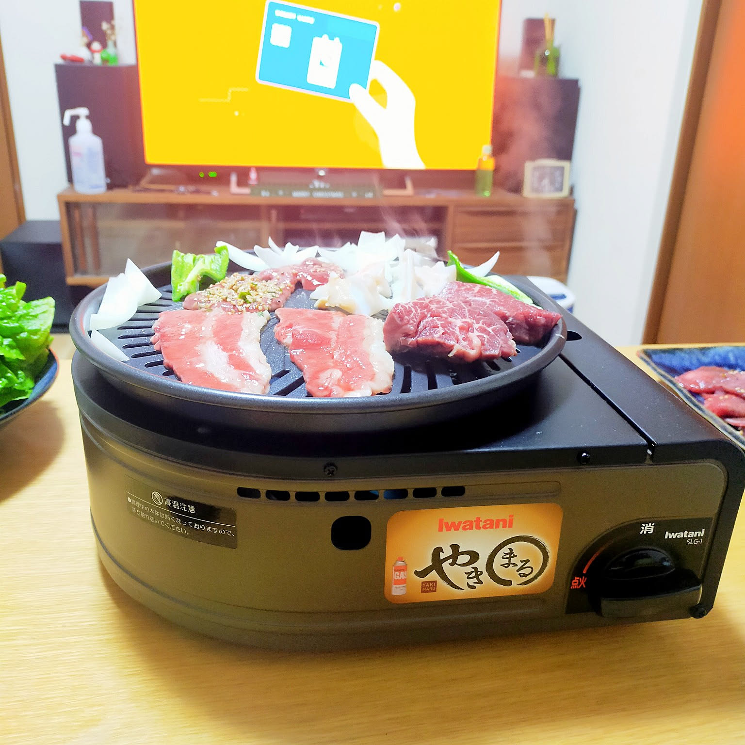 An Iwatani Yakimaru grill cooking sliced meat for an indoor tabletop yakiniku dinner.
