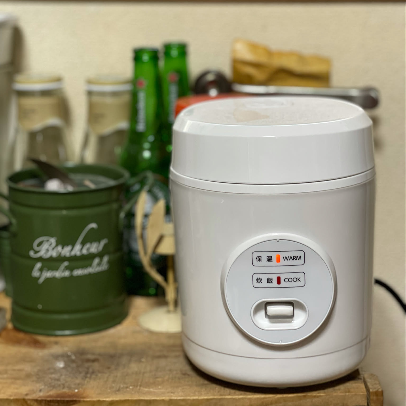 A compact white Yamazen rice cooker shown close-up on a small kitchen shelf.