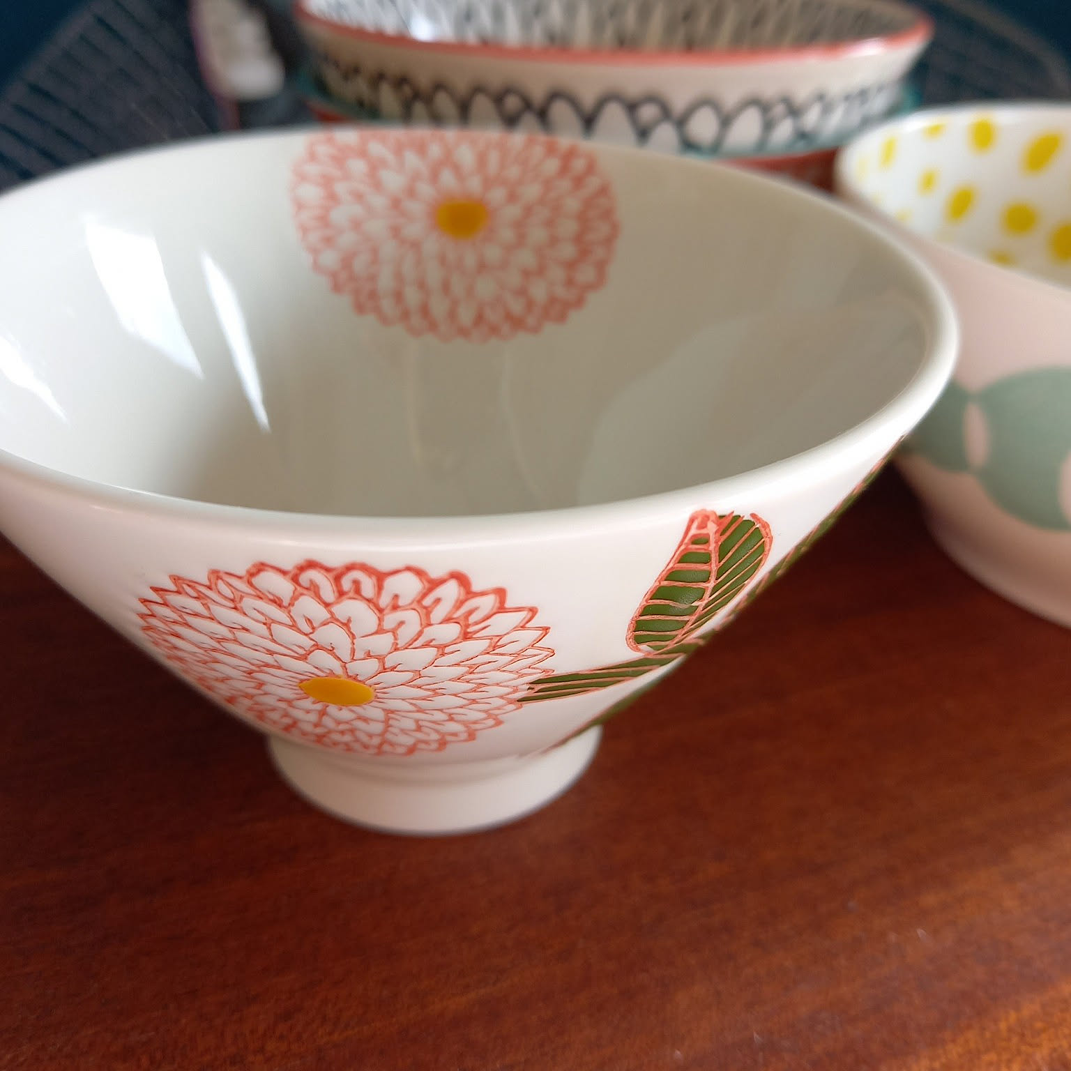 Close-up of a white Japanese rice bowl with pink and green floral pattern.