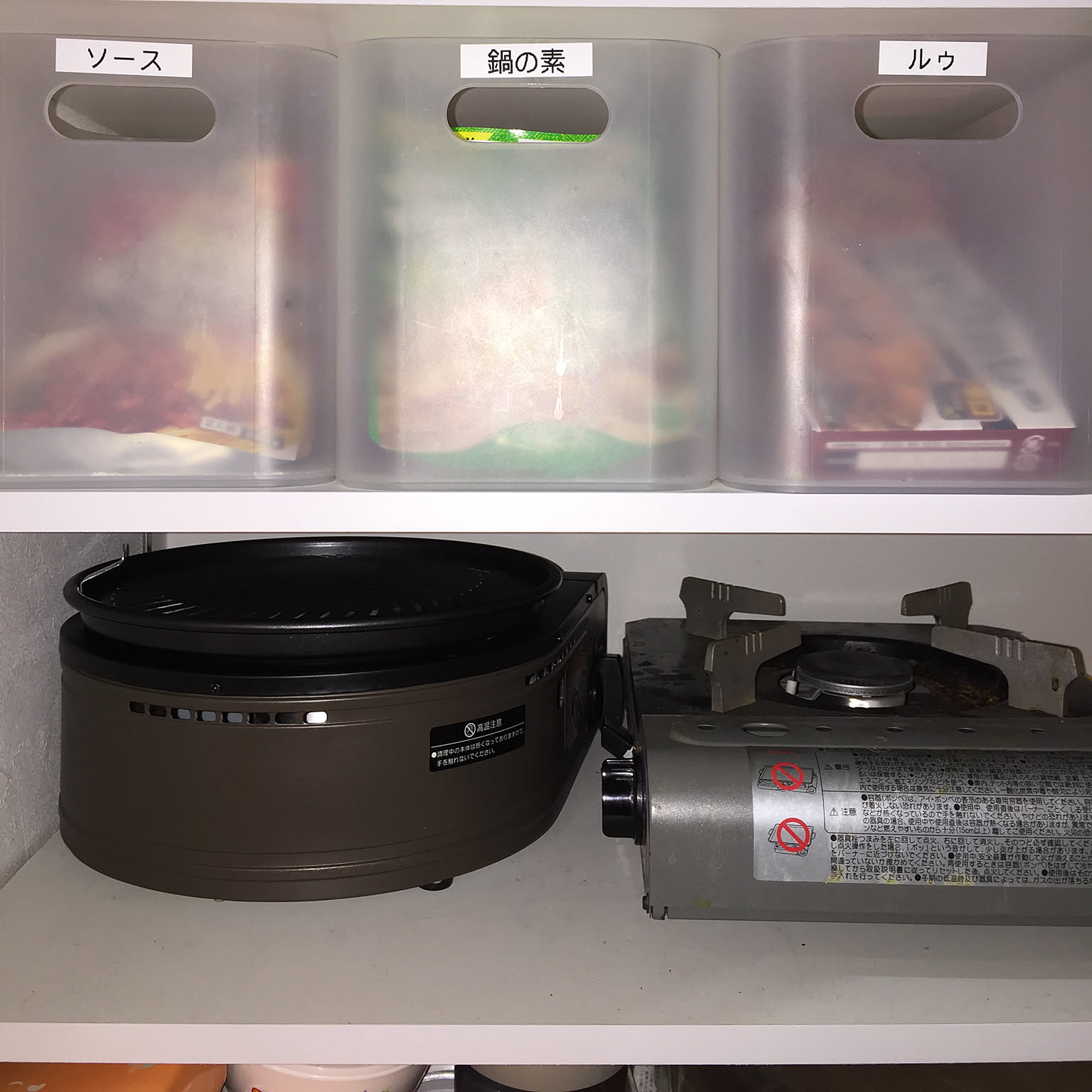 An Iwatani Yakimaru grill stored on a pantry shelf beside another cassette stove.