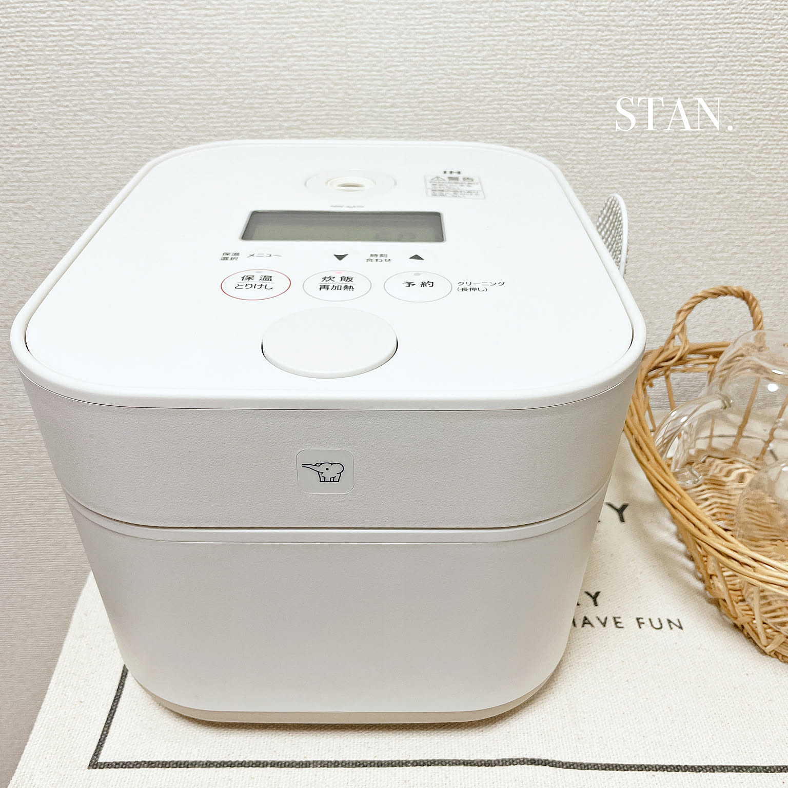 A white Zojirushi STAN. rice cooker shown close-up on a kitchen appliance shelf.