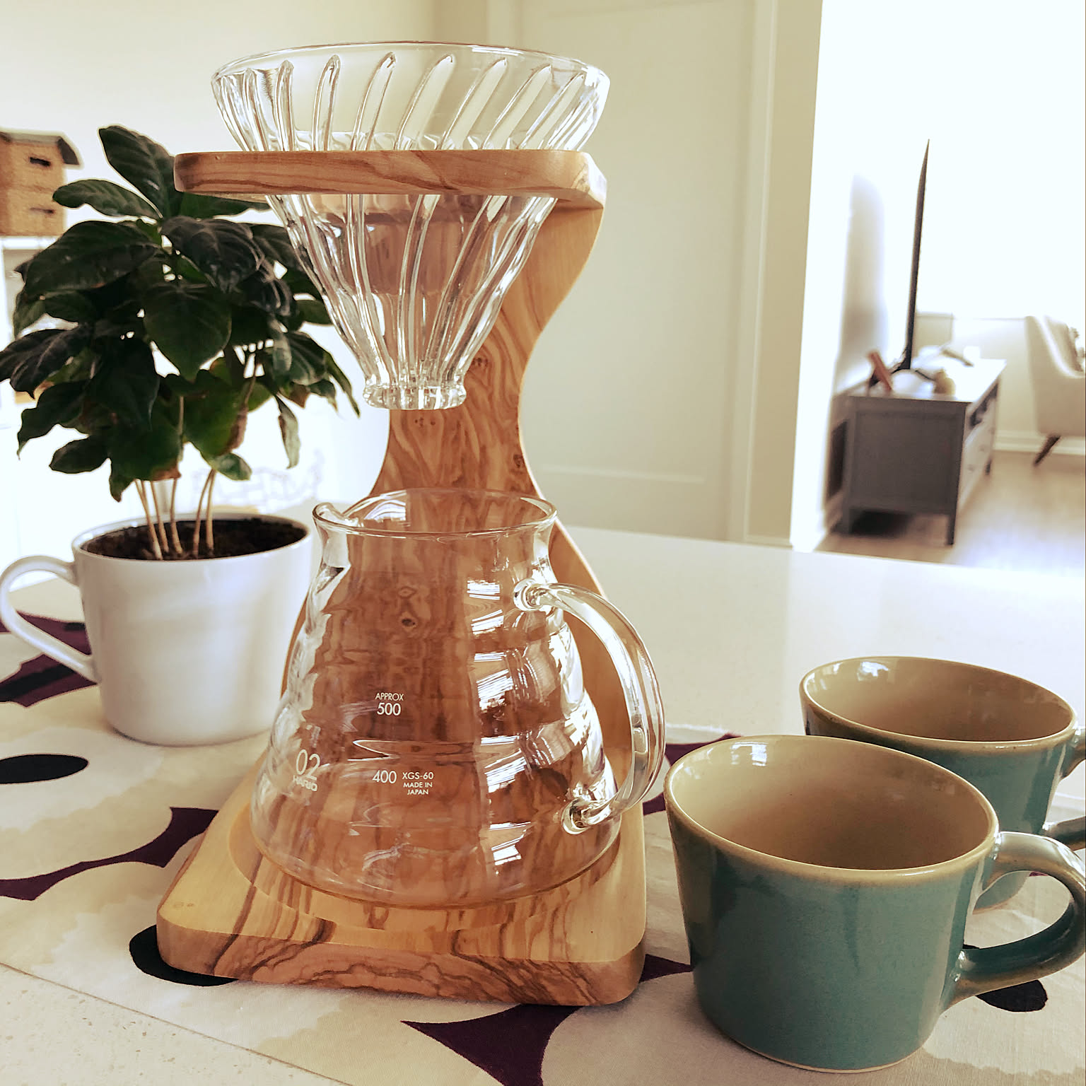 A compact coffee shelf with HARIO drippers, glass servers, jars, and beans arranged in a Japanese kitchen.